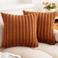 Two rust brown striped faux fur pillow covers on a cream sofa