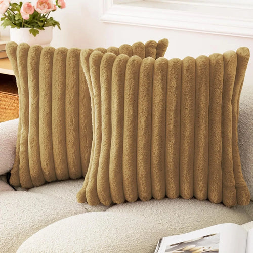 Two camel striped faux fur pillow covers on a cream sofa