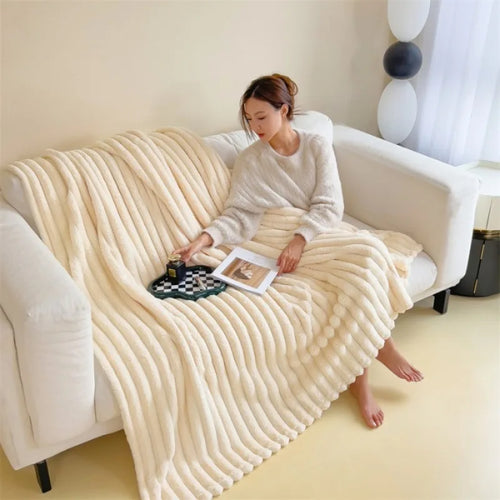 Off-white ribbed faux fur throw blanket draped over a white sofa