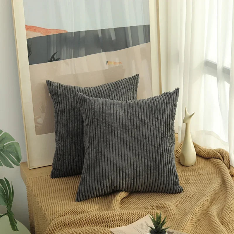 Two dark gray corduroy pillow covers on a window bench