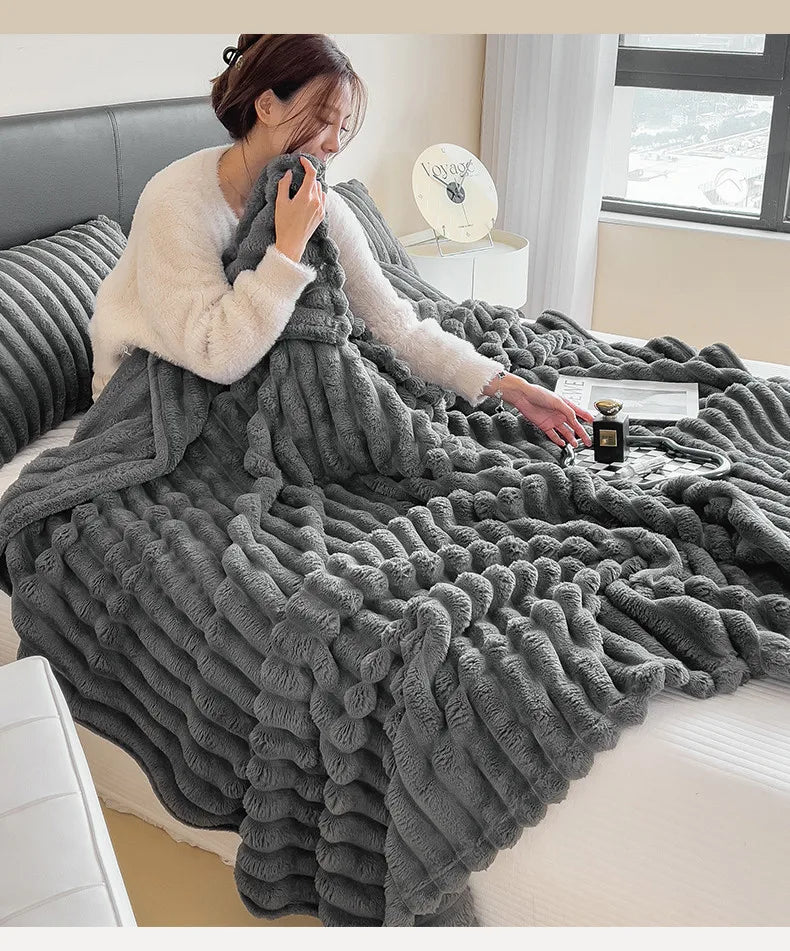 Person wrapped in a dark gray ribbed faux fur throw blanket