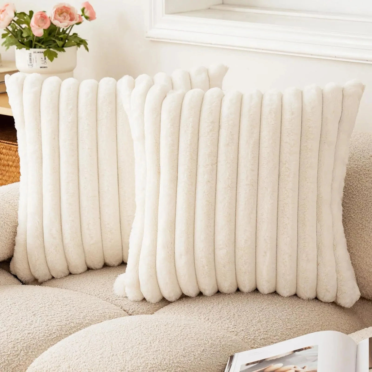 Two ivory striped faux fur pillow covers on a cream sofa