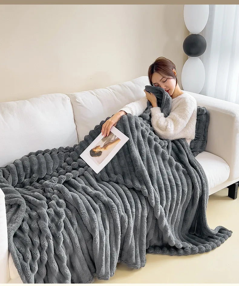 Person resting on a sofa under a dark gray ribbed faux fur throw