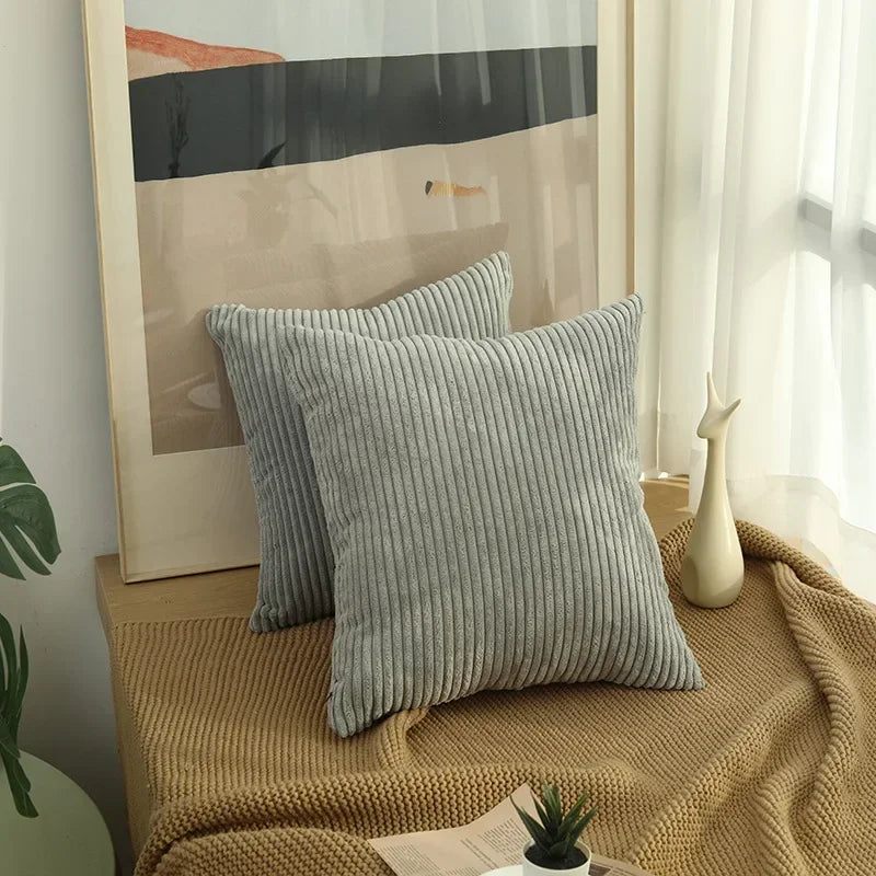 Two silver gray corduroy pillow covers on a window bench