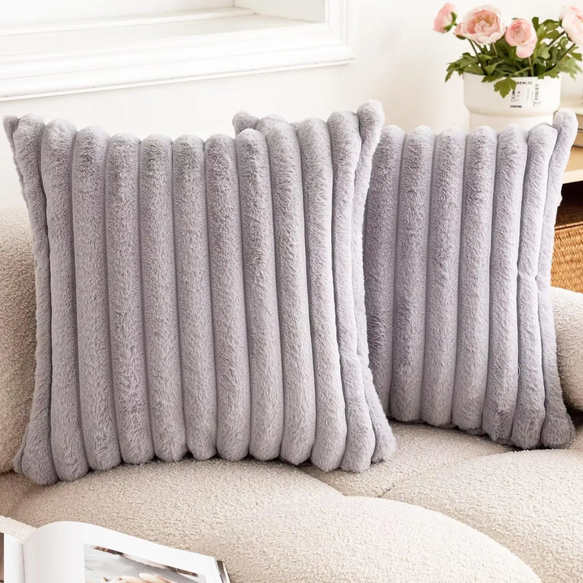 Two gray striped faux fur pillow covers on a cream sofa