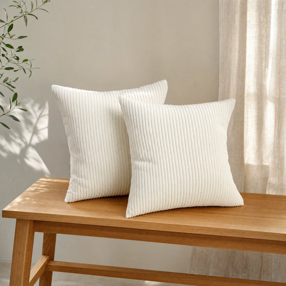 Styled image: two white corduroy pillow covers on an oak bench in a sunlit room